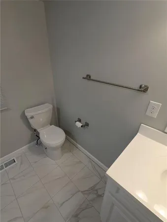 a bathroom with a toilet and a wooden floor