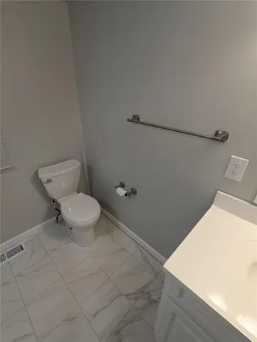 a bathroom with a toilet and a wooden floor
