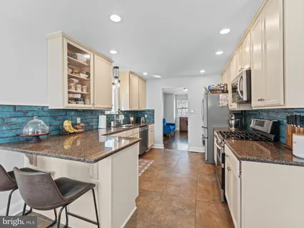 a kitchen with stainless steel appliances granite countertop a stove top oven a sink a refrigerator and white cabinets