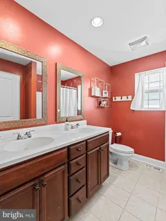 a bathroom with a double vanity sink toilet and a mirror