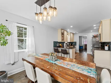 a dining room with wooden floor a chandelier a wooden table and chairs