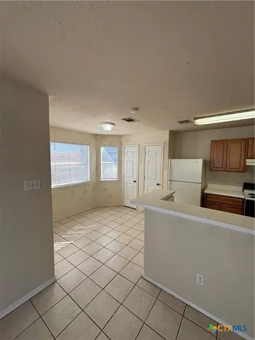 a view of kitchen and empty room with windows