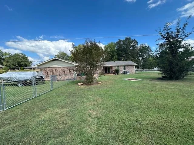 a view of a yard in front of a house with plants and large tree