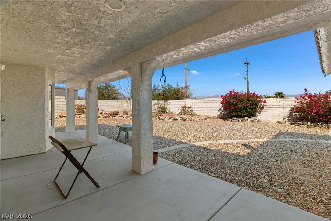 2055 Cholla Way Laughlin, NV 89029 - Photo 51 of 87 An inviting covered patio offers a cool respite, overlooking a low-maintenance gravel yard with vibrant flowering shrubs.