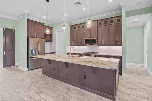 a large kitchen with stainless steel appliances kitchen island granite countertop a refrigerator and a sink