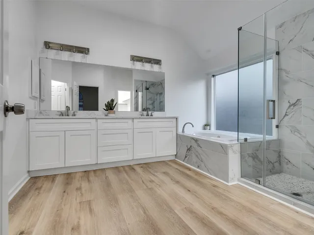 a spacious bathroom with a double vanity sink mirror and bathtub