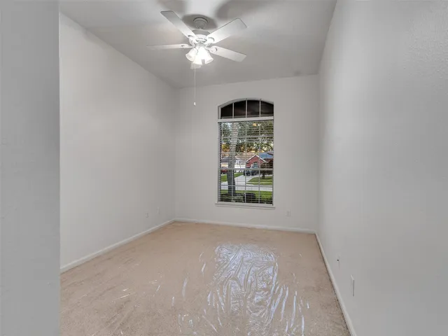 an empty room with windows and ceiling fan