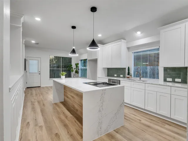 a kitchen with a stove a sink a kitchen island with wooden cabinets and floor