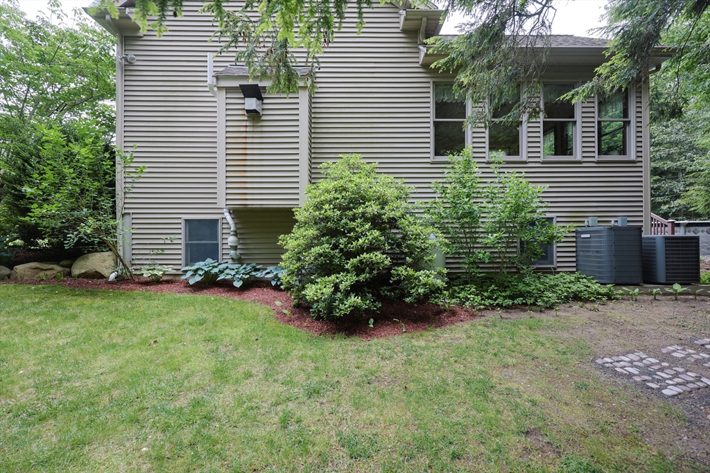 70 Azalea Way Hanson, MA 02341 - Photo 40 of 42 a view of a backyard with plants and a large tree
