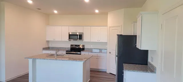 a kitchen with stainless steel appliances a refrigerator a stove a microwave and white cabinets