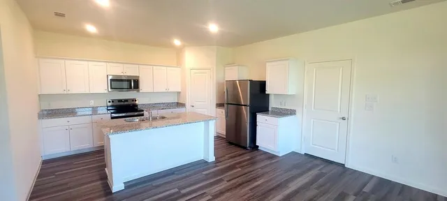 a kitchen with a refrigerator a stove top oven a counter space and wooden floor