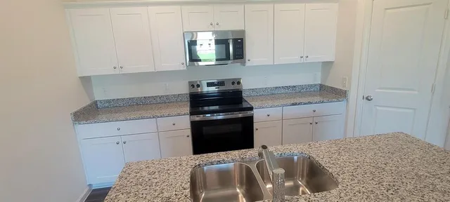 a kitchen with granite countertop white cabinets and stainless steel appliances