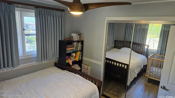 a bedroom with a bed a dresser and a large window