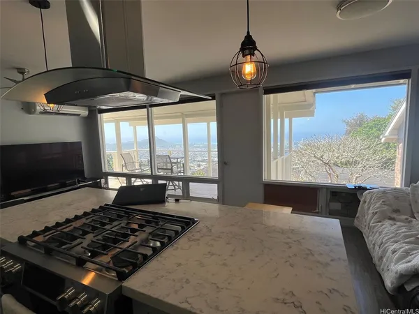 a kitchen with granite countertop a stove and a flat screen tv