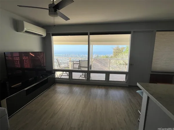 a view of empty room with wooden floor and fan