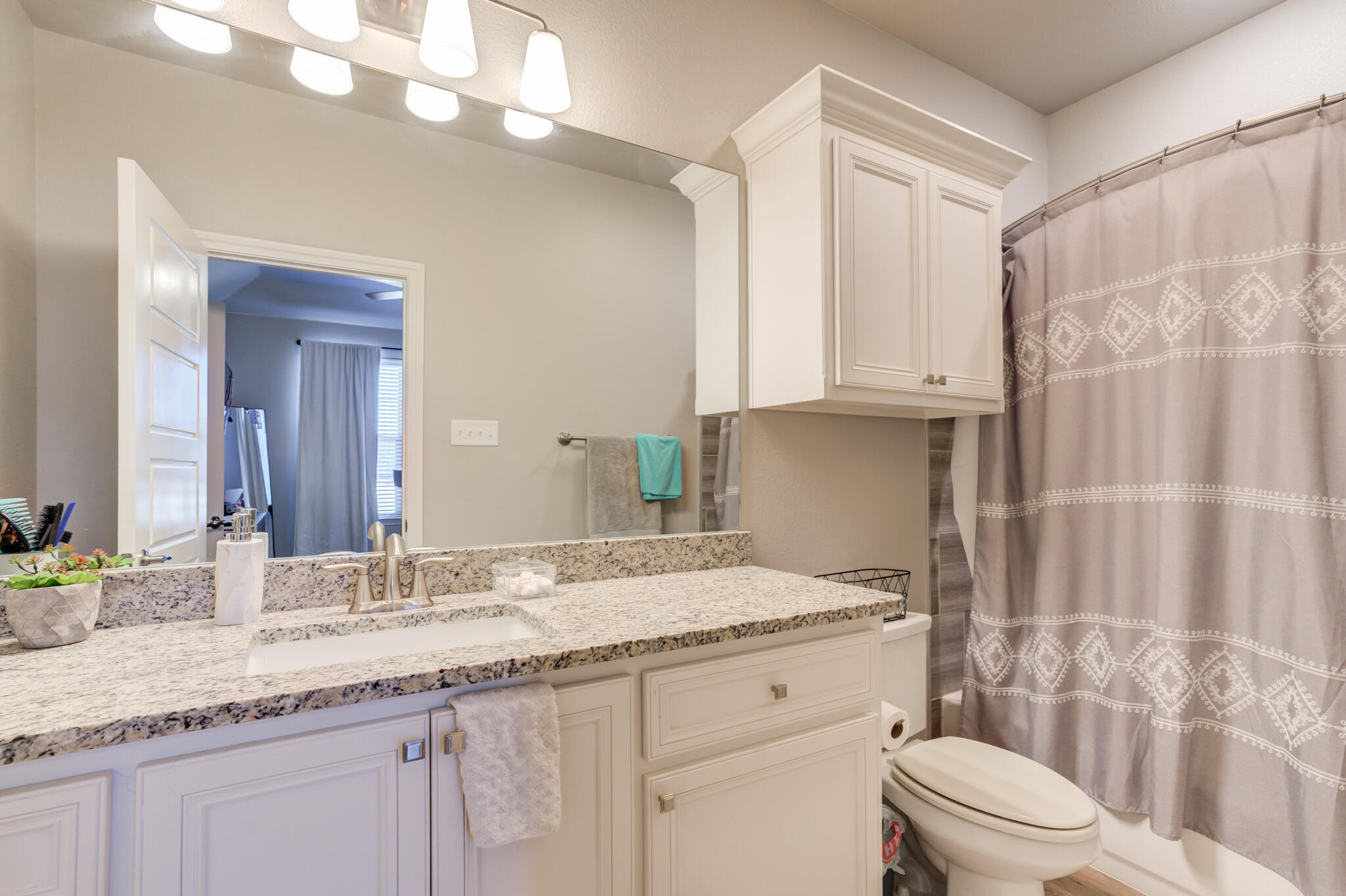 9609 Inverness Avenue Lubbock, TX 79424 - Photo 11 of 17 a bathroom with a granite countertop sink a toilet and shower