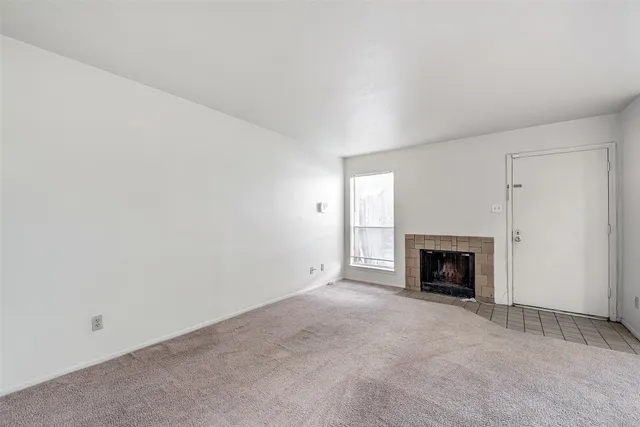 a view of an empty room with a fireplace and a window