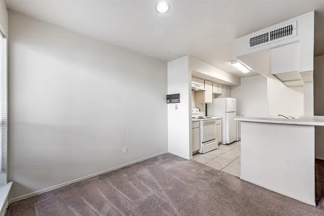 a view of a kitchen with white cabinets and refrigerator