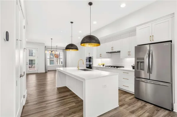 a kitchen with stainless steel appliances kitchen island granite countertop a stove a sink and white cabinets with wooden floor