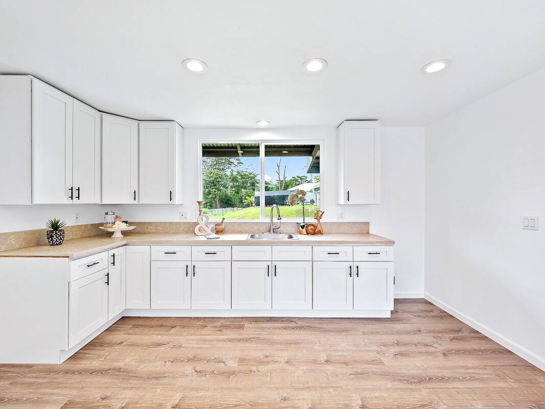 1907 Uhaloa Road Hilo, HI 96720 - Photo 14 of 23 a large white kitchen with a sink and dishwasher with wooden floor