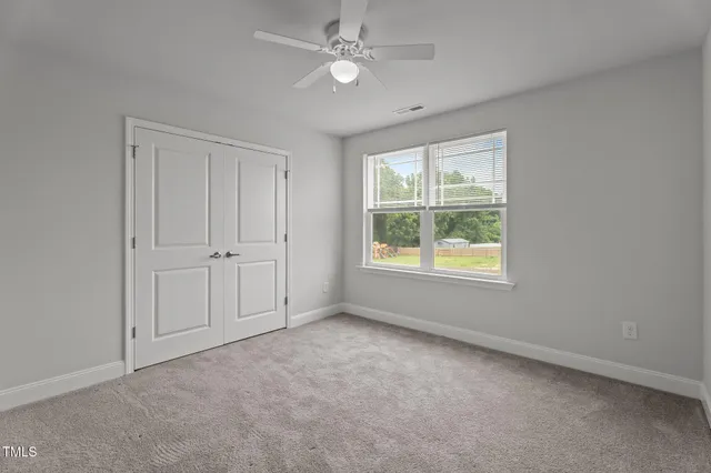 an empty room with windows and fan