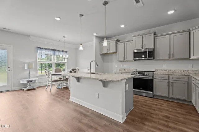 a kitchen with stainless steel appliances granite countertop a sink dishwasher a stove and a refrigerator with wooden floor