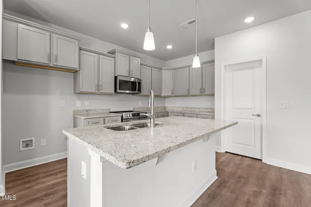 a kitchen with kitchen island granite countertop a sink stove and refrigerator