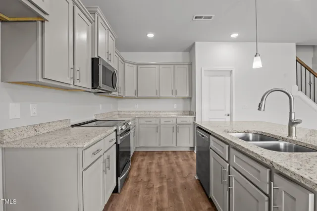 a kitchen with stainless steel appliances granite countertop a sink stove and cabinets