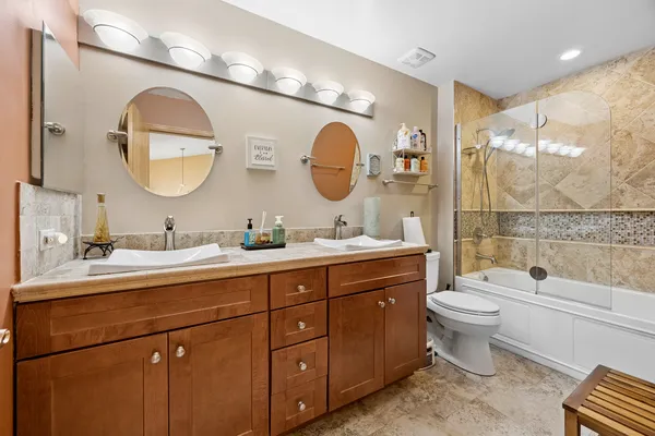 a spacious bathroom with a toilet a double vanity and a mirror