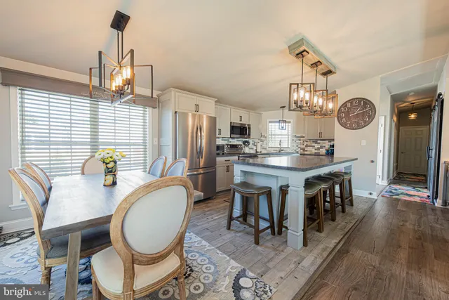 a dining room with chandelier fan and wooden floor