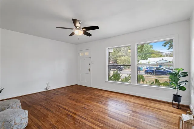 a view of an empty room with wooden floor and a window