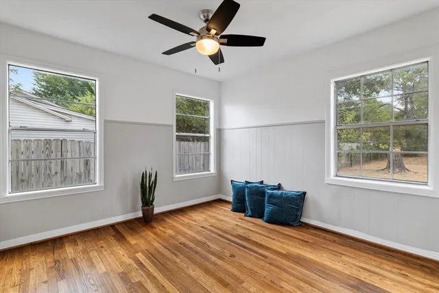 a view of an empty room with a window and wooden floor