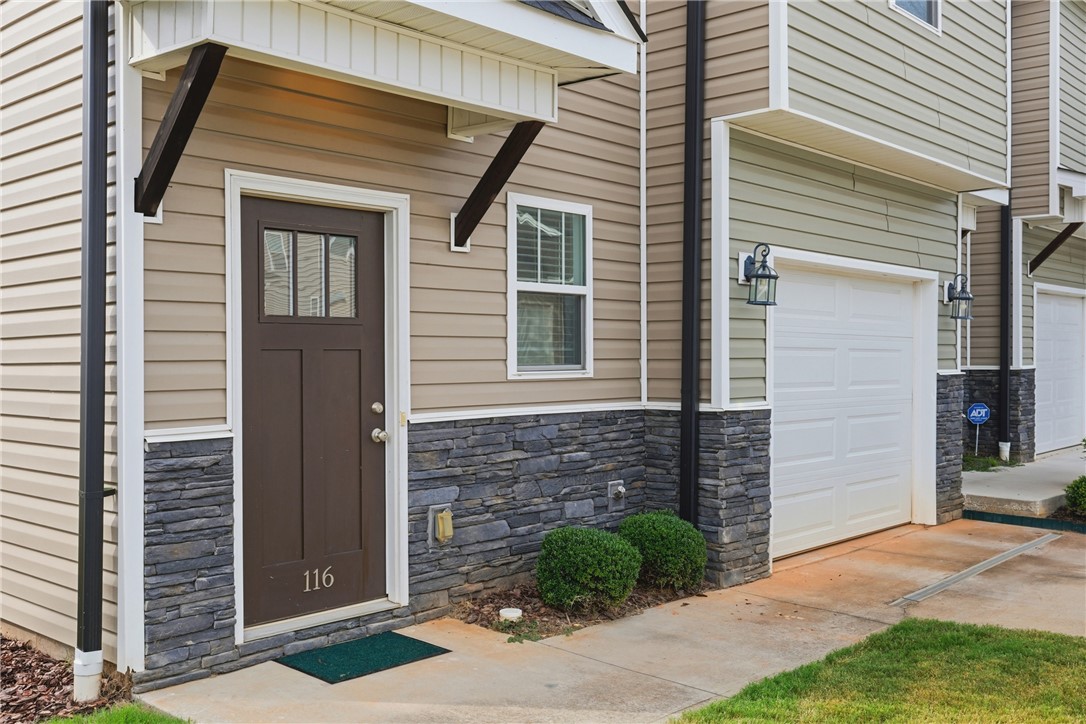 116 Ventura Street Anderson, SC 29621 - Photo 2 of 27 A welcoming stone-accented entryway features a classic paneled front door and adjacent garage.