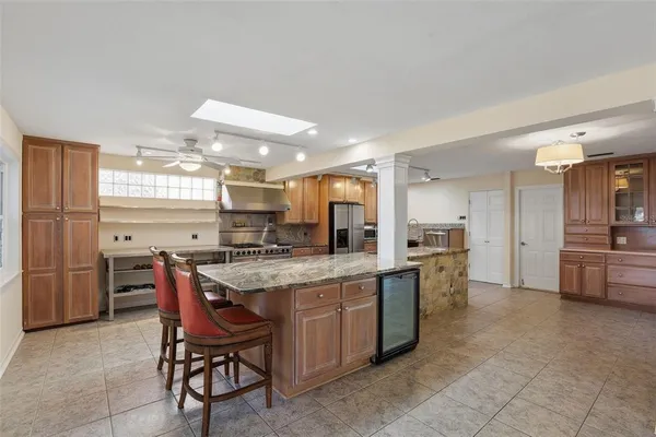 a kitchen with stainless steel appliances granite countertop a table chairs sink and cabinets