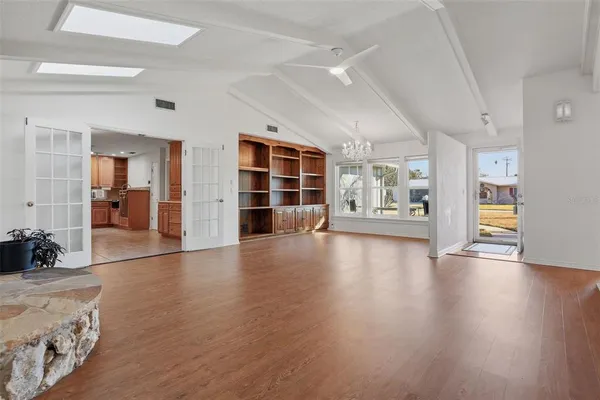 a view of an empty room with wooden floor and a window