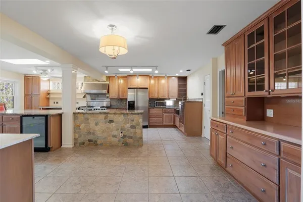 a large kitchen with kitchen island granite countertop a stove a sink a refrigerator and a cabinets