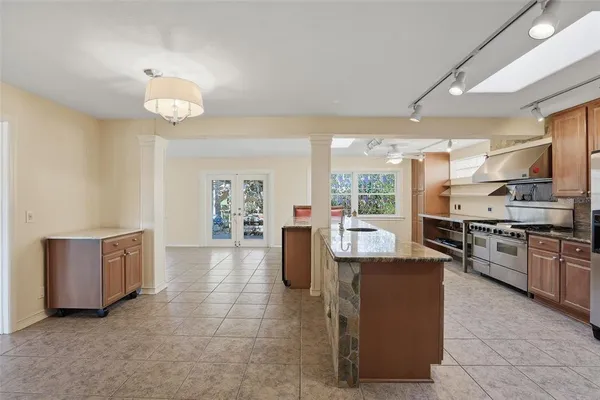 a large kitchen with granite countertop a large counter top cabinets appliances and a ceiling fan