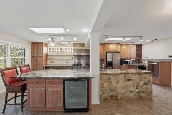a kitchen with kitchen island a counter top space a sink stainless steel appliances and cabinets