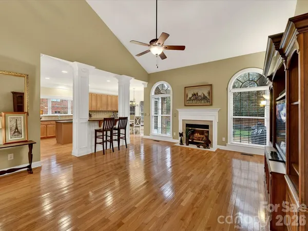 a view of a livingroom with furniture a fireplace wooden floor and windows