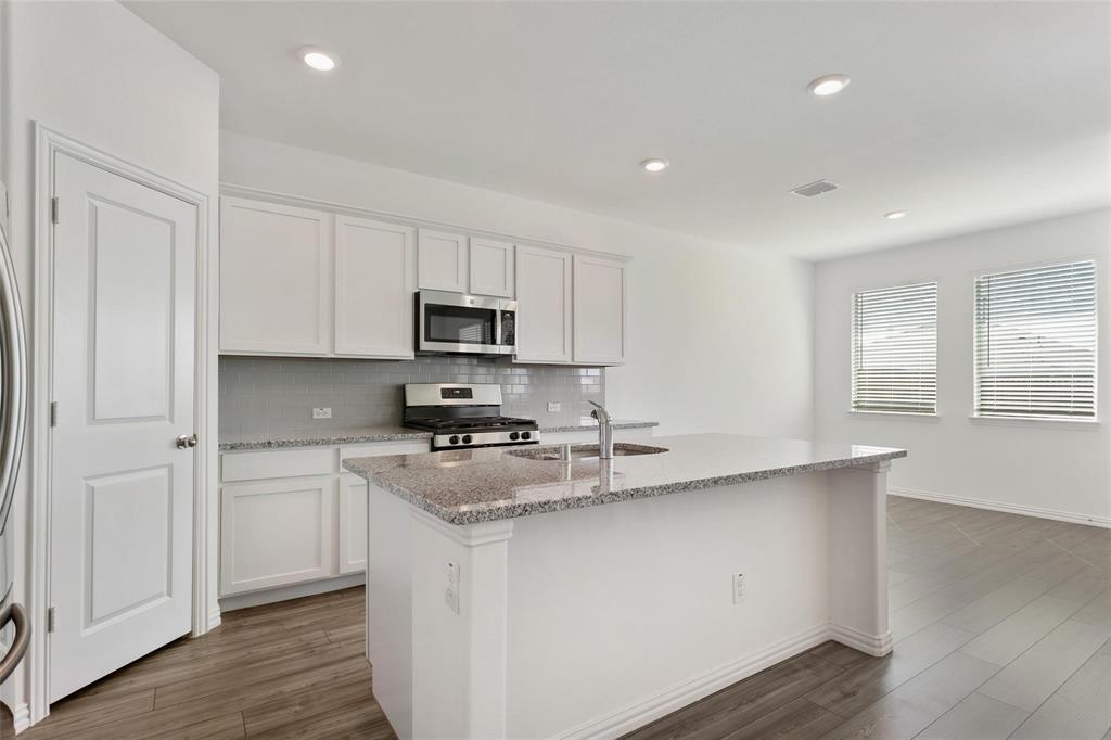 2157 Clarion Drive Forney, TX 75126 - Photo 14 of 28 a kitchen with stainless steel appliances granite countertop a stove a sink and white cabinets