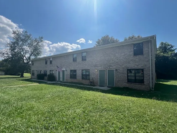 a view of a house with a yard and a large tree