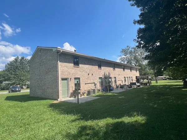 a view of a yard in front of a house with a large tree