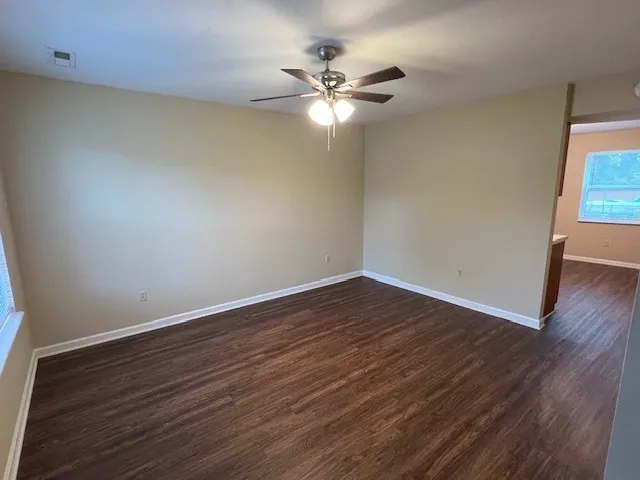 a view of an empty room with wooden floor and a window