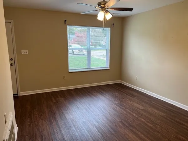 a view of an empty room with wooden floor and a window