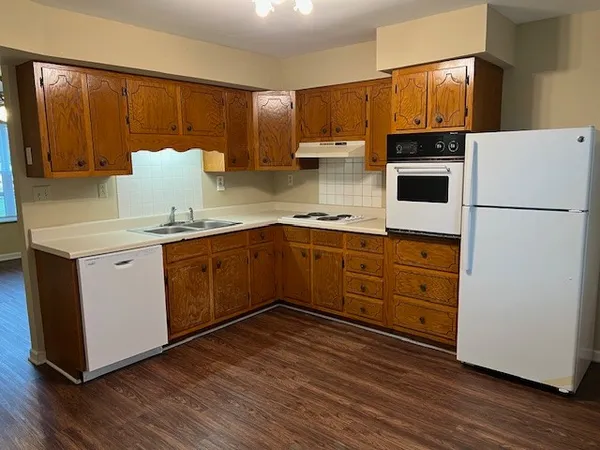 a kitchen with wooden cabinets and white appliances