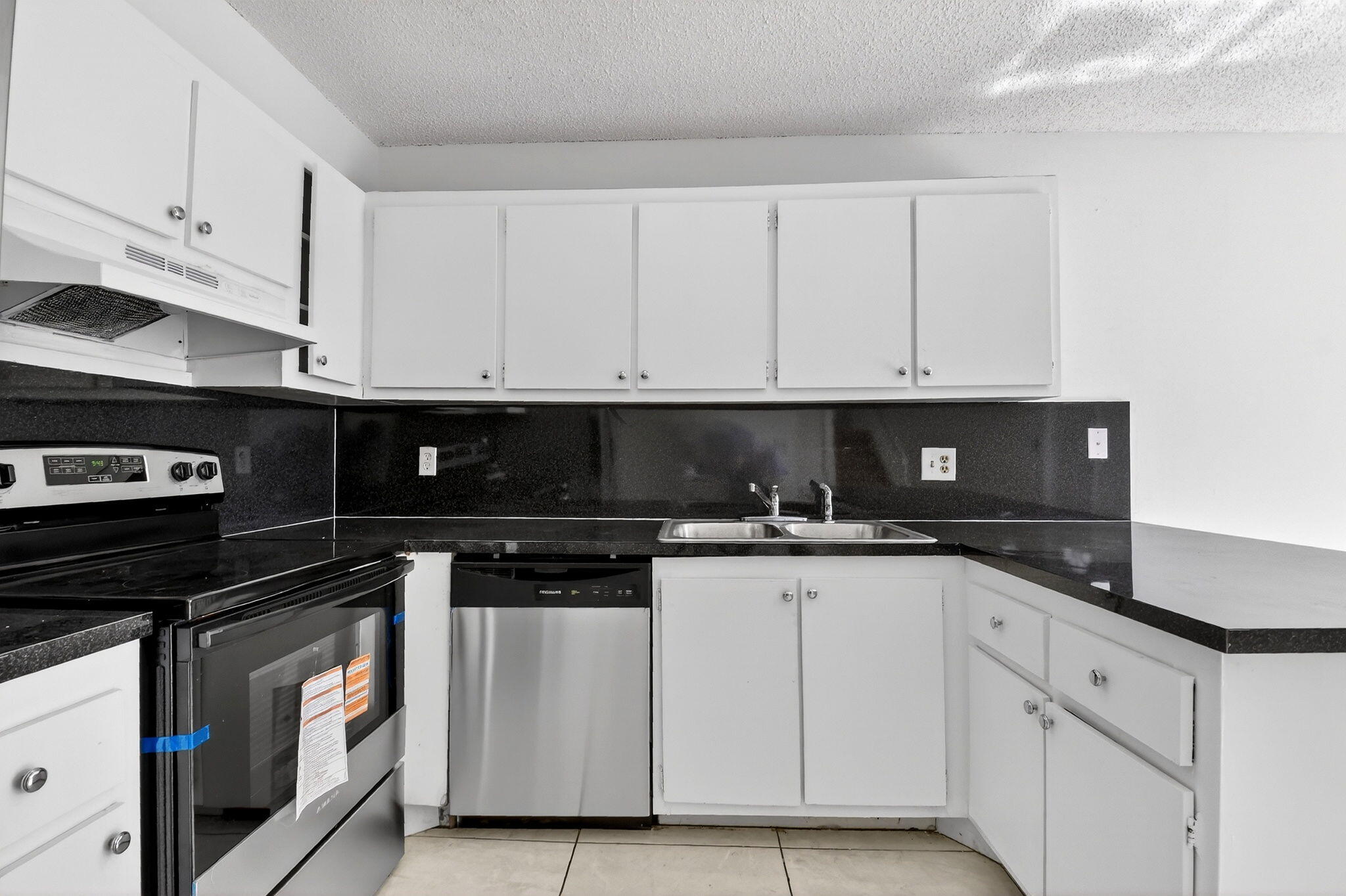 136 Woodland Road Palm Springs, FL 33461 - Photo 12 of 42 a kitchen with granite countertop white cabinets and black appliances