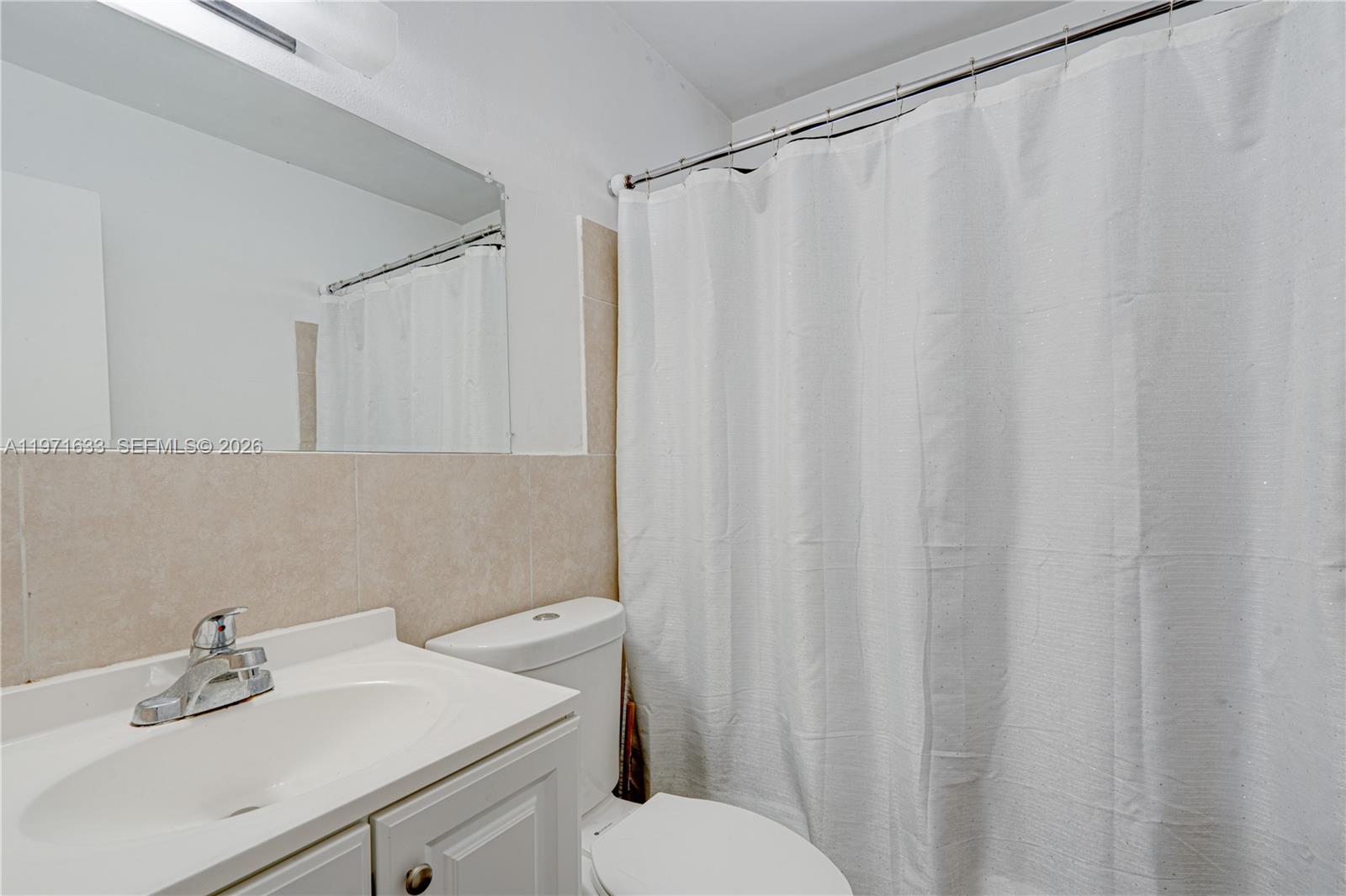 502-504 Phippen Waiters Road, Unit 4 Dania Beach, FL 33004 - Photo 14 of 16 a bathroom with a sink a toilet and shower curtain