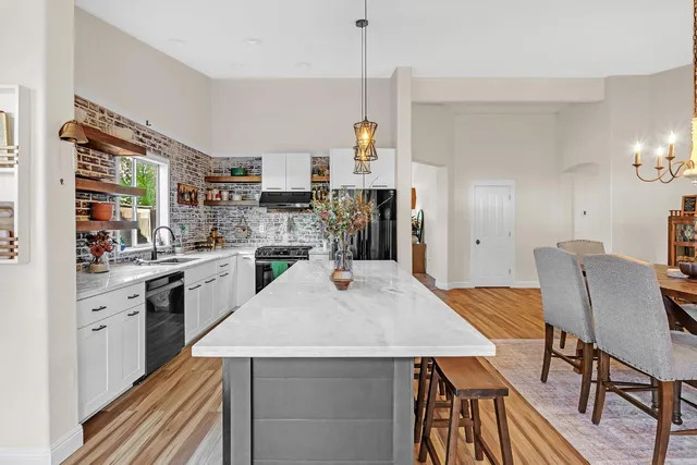 a kitchen with stainless steel appliances kitchen island a table chairs and a refrigerator
