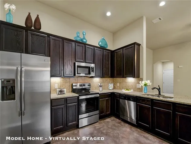 a kitchen with kitchen island granite countertop a sink cabinets and stainless steel appliances