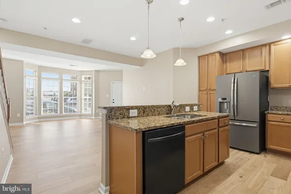 a kitchen with stainless steel appliances granite countertop a refrigerator a sink a stove and a wooden floors